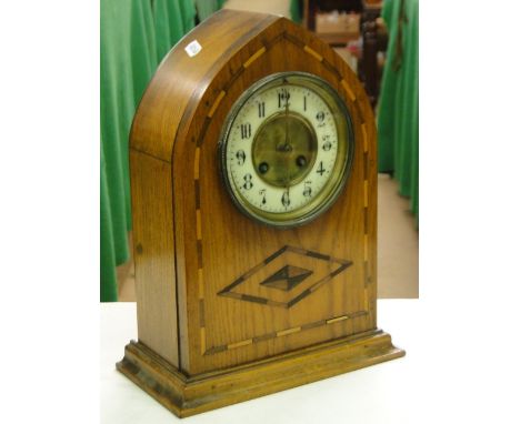 A marquetry inlaid lancet top mantel clock with enamelled dial and 2-train movement.