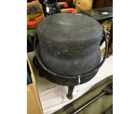 A Cast iron cauldron on tripod supports, with cover