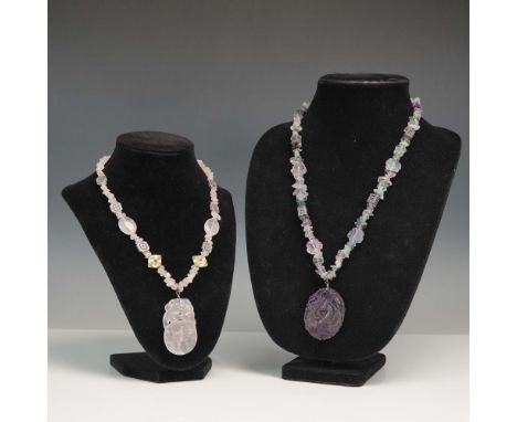 Pair of artisan-crafted necklaces featuring detailed carved stone pendants and decorative accent beads. One necklace is strun