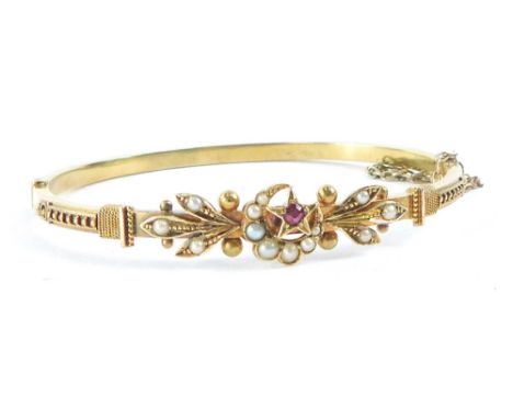 A Victorian/Edwardian hinged bangle, with crescent moon and star decoration, set with ruby and seed pearl, with filigree type