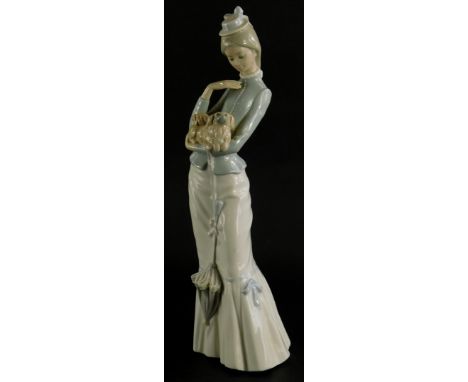 A Lladro porcelain figure of a tall lady, holding a Pekingese dog whilst holding a parasol, 38cm high.