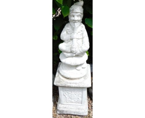 A composition figure of a gnome smoking a pipe, on a rectangular plinth, 107cm high overall.