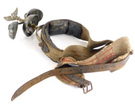 An unusual leather and canvas horse harness, mounted with three bells and an eagle finial.