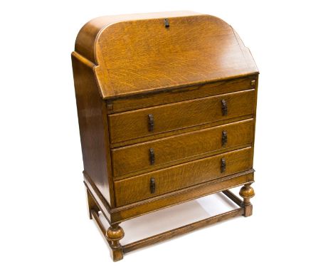 An Art Deco oak bureau, cushion moulded fall front opening to reveal a pigeon holed interior, over three drawers, each with f