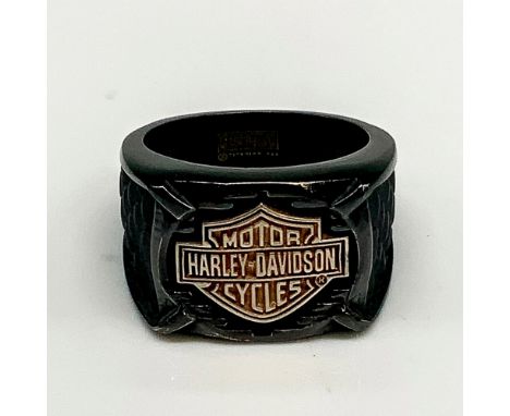 Black band with a large copper tone Harley Davidson logo in the front and textured dark grey scales carved on either side. Ti