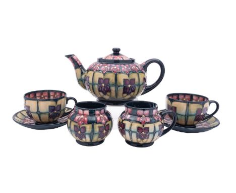 A Moorcroft part tea service in the Violets pattern, comprising a teapot and cover, milk jug [damaged] sugar bowl and pair of