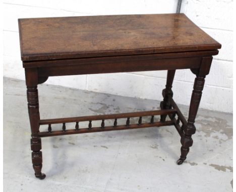 A late Victorian walnut card table with rectangular fold-over top on ring-turned supports united by galleried stretchers, wid