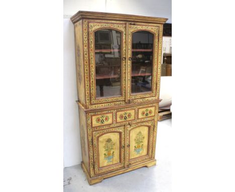 An Indian yellow-painted and waxed cabinet, hand-painted with floral decoration, twin glazed doors to upper cabinet with two 