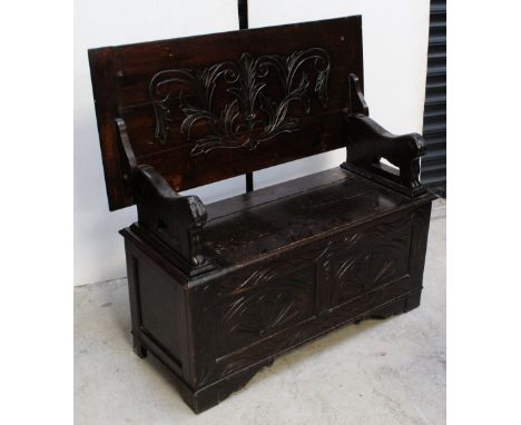 A 20th century oak monks' bench with carved panels to front, on carved bracket supports, height 69cm.