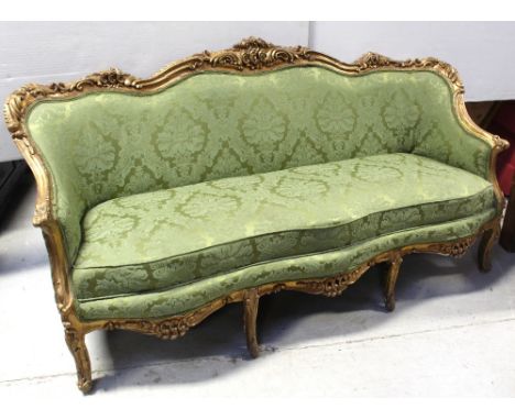 A 19th century Romanesque gilded sofa, curved back rail carved with scrolls and acanthus leaves to curved arms, serpentine-fr