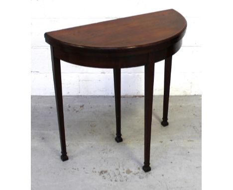 An Edwardian mahogany demi-lune fold-over card table with pull-out recess, on four tapering supports, width 76cm.