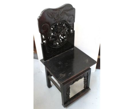 An Oriental ebonised hall chair with carved back to square seat above carved base.