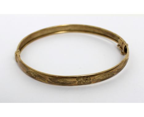 A 9ct yellow gold hinged bangle with floral engraved detail, approx 7.2g.