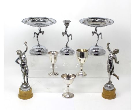 A pair of silvered figures raised on circular plinths, a pair of chrome-plated tazzas, three goblets and a single candlestick