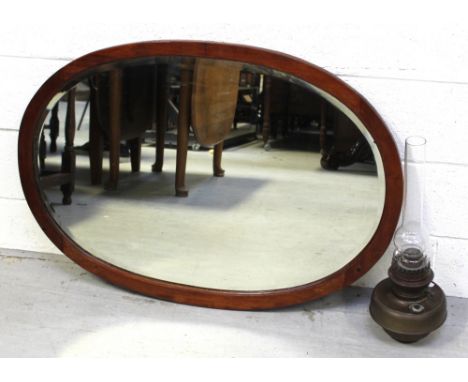 An Edwardian mahogany-framed oval mirror and an oil lamp (2).