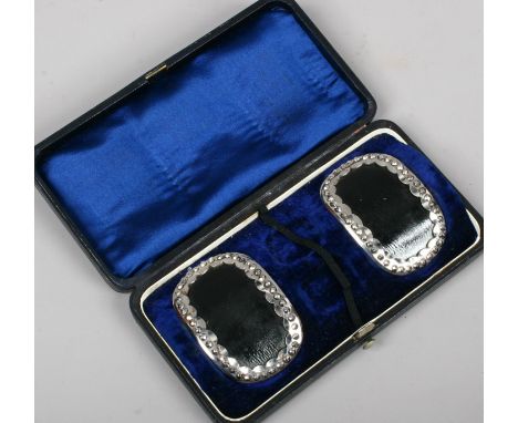 A pair of cased antique cut steel shoe buckles with leather mounts.