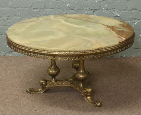 A circular onyx coffee table raised on gilt metal tripod base.