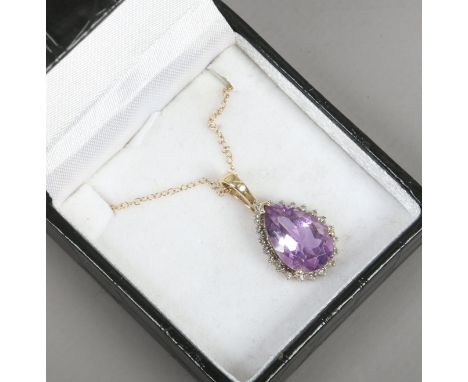 A 9ct gold amethyst tear drop pendant with diamond border and set on a 9ct gold trace chain. 