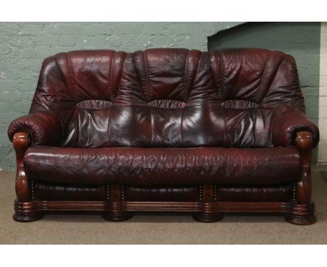 An oxblood leather and carved hardwood three seat sofa.