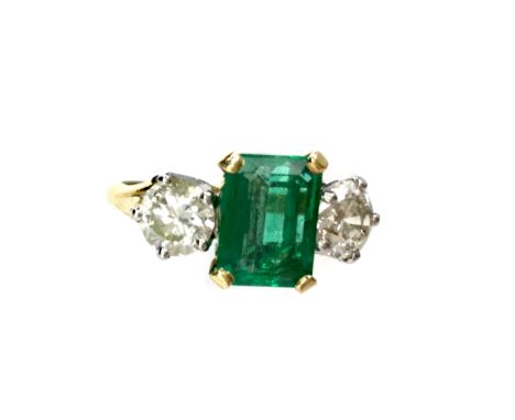 GREEN GEM SET AND DIAMOND THREE STONE RING, the central four claw mounted step cut green gem flanked by brilliant cut diamond