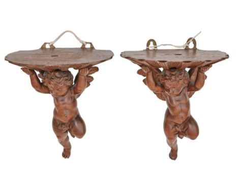 A pair of Continental carved walnut wall brackets, in the form of winged cherubs, early 20th c, 19cm x 16cm One bracket with 