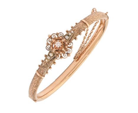 A diamond and split pearl bangle, early 20th c, in gold, applied with filigree work and centred by a single old cut diamond, 