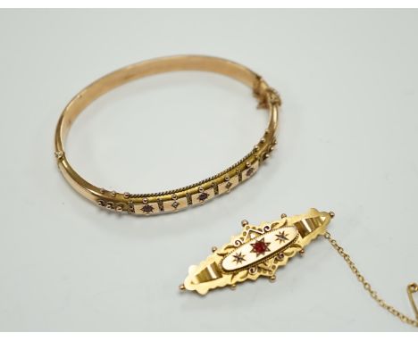 An Edwardian 9ct gold ruby and diamond chip set hinged bangle and a similar yellow metal, ruby and diamond chip set bar brooc
