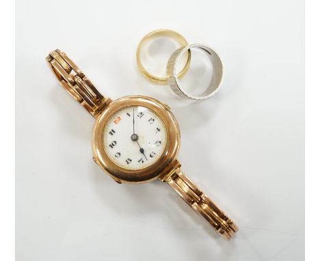 A textured white metal (stamped platinum) band, 7 grams, an 18ct gold band,4.5 grams and a 9ct gold manual wind wrist watch, 