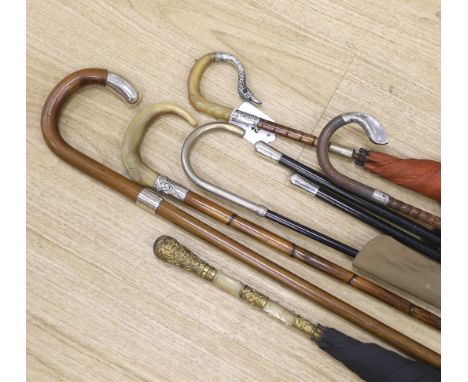 Various vintage umbrellas and walking sticks, three with silver mounted handles and two ebonised swagger sticks with silver t