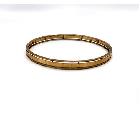 A 9ct yellow gold solid bangle with a ribbed central faceted top by A. Bros 11.2gms.