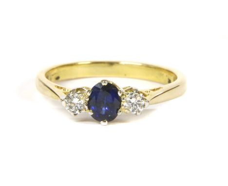 An 18ct gold sapphire and diamond three stone ring, an oval mixed cut sapphire with a brilliant cut diamond at each side, all