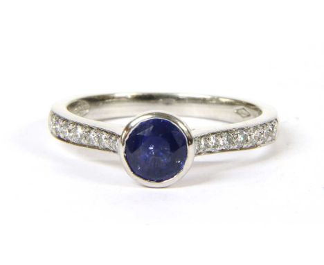 A platinum sapphire and diamond ring, a circular mixed cut sapphire, rub set to a plain collet, with tapered shoulders grain 