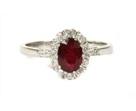 An 18ct gold ruby and diamond cluster ring, an oval mixed cut ruby, claw set to surround of brilliant cut diamonds. A brillia