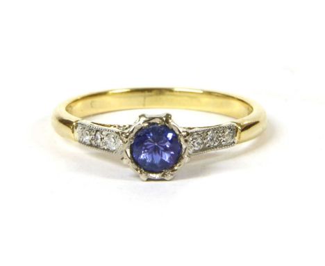 An 18ct gold tanzanite and diamond ring, a circular mixed cut tanzanite, grain set to a white gold illusion collet and chenie