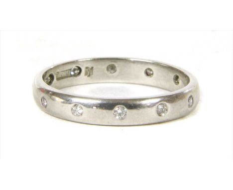 A platinum diamond wedding ring, by Charles Green &amp; Sons. A row of brilliant cut diamonds, gypsy set to the D section sha