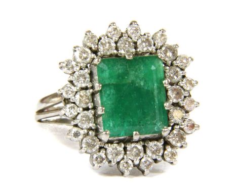 An 18ct gold emerald and diamond rectangular cluster ring, c.1970, an emerald cut emerald claw set at the centre, surrounded 