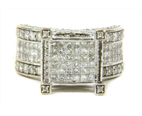 A white gold diamond ring, the square head with invisible set princess cut diamonds, to crossover gallery, grain set with bri