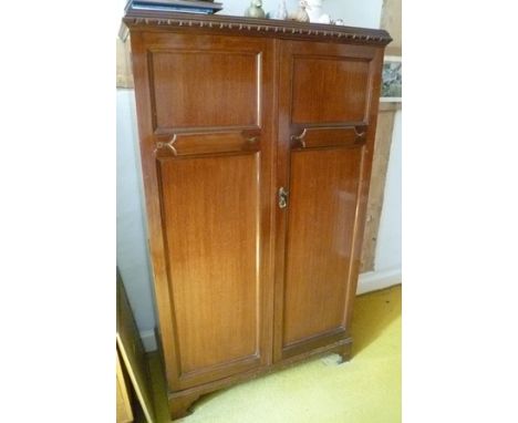 A MAHOGANY TWO DOOR SMALL WARDROBE with panelled twin doors, raised on bracket feet 
