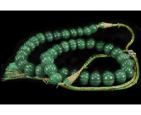 An Indian treated emerald bead necklace,  composed of melon cut uniform beads, to a silk tie