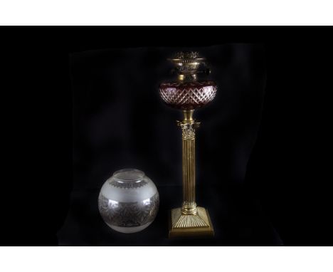 A 19th century cranberry-flashed glass oil lamp, on a brass Corinthian column base lamp, 55cm high, with etched glass shade
w