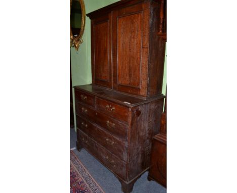 ~ A George III oak press cupboard late 18th century with a bold cornice above two cupboard doors enclosing shelves, the base 