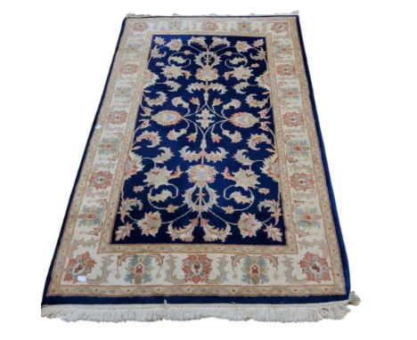 A woollen rug, with scrolling foliage on a blue ground, banded cream border, 150cm long, 95cm wide