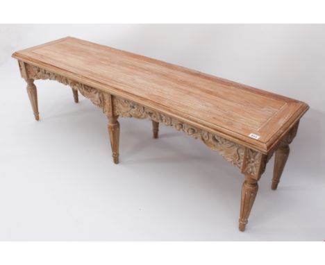 An Oriental carved, limed hardwood long stool or bench - modern, the cleated, moulded seat over a foliate carved and pierced 
