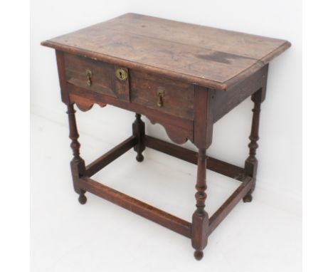 An early 18th century joined oak single-drawer side table - the boarded, moulded top over a single drawer with original drop 