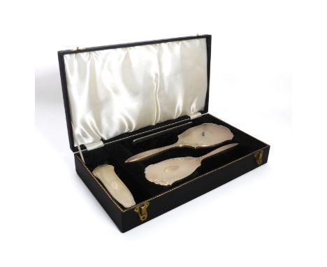 An Elizabeth II cased four-piece silver mounted dressing table set - Henry Bushell &amp; Co., Birmingham 1963, shaped form wi