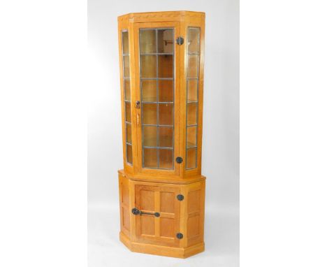 A Robert 'Mouseman' Thompson light oak corner cabinet,  with a top frieze over lead glazed door and side panels, over a singl