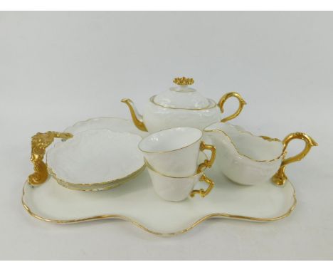 A Limoges porcelain early 20thC tete-a-tete, with rococo moulding, gilt highlighted, painted marks, comprising twin handled t