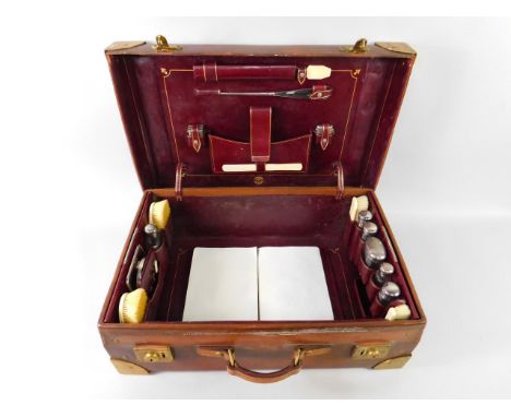 A Finnigans early 20thC tan leather and brass bound travelling case, with a red Morocco fitted interior, containing a sharing