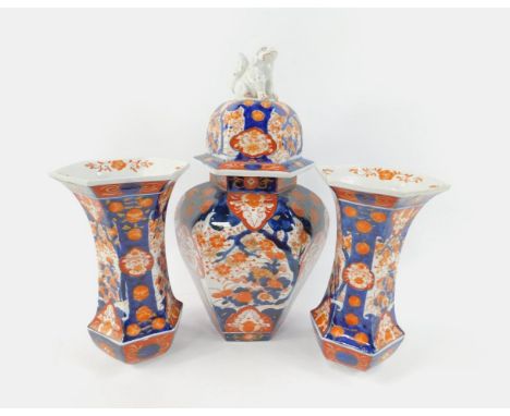 A Japanese Meiji period porcelain Imari garniture, comprising hexagonal vase and cover with the lion dog finial, and a pair o