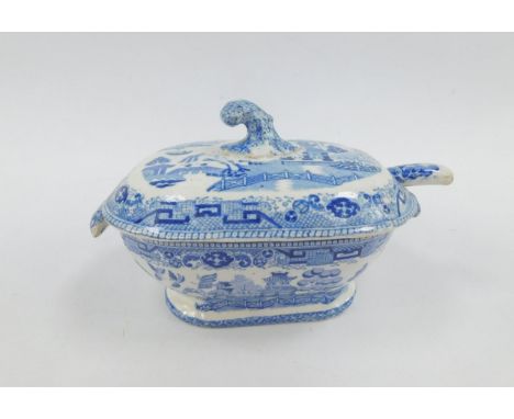 An early 19thC pottery blue and white sauce tureen, cover and ladle decorated in the Willow pattern.